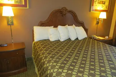 a hotel room with a bed with white pillows at American Inn Stockton in Stockton