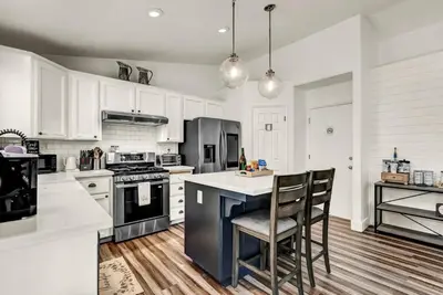 a kitchen with white cabinets and a kitchen island with chairs at Magnolia Peaceful Vibes Cozy Near Hospital in Hanford