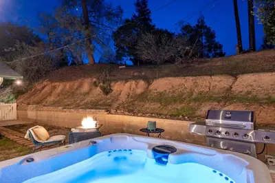 a jacuzzi tub in a backyard with a grill at Manic Mountain Forest Cabin 3 miles from Bass Lake in Oakhurst