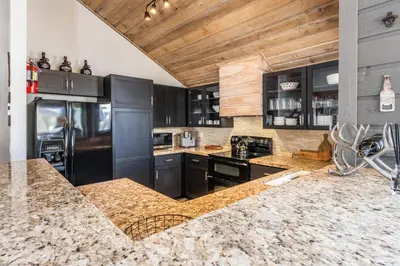 a kitchen with black cabinets and a marble counter top at Snowcreek II 2 plus loft 2 bathroom end unit condo sleeping 8 people with amazing mountain view in Mammoth Lakes