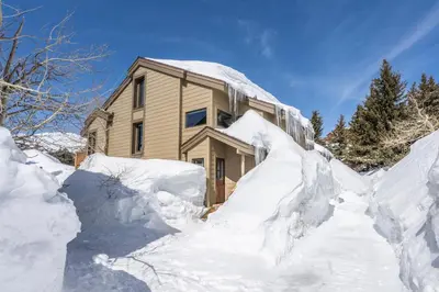 a house covered in snow with a pile of snow at Snowcreek II 2 plus loft 2 bathroom end unit condo sleeping 8 people with amazing mountain view in Mammoth Lakes