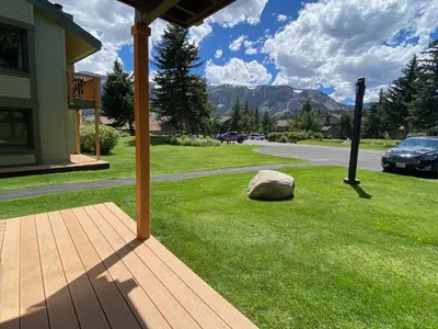 a porch of a house with a rock on the grass at Snowcreek II 2 plus loft 2 bathroom end unit condo sleeping 8 people with amazing mountain view in Mammoth Lakes
