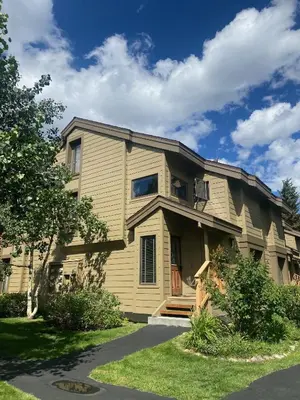 a yellow house with a porch on a street at Snowcreek II 2 plus loft 2 bathroom end unit condo sleeping 8 people with amazing mountain view in Mammoth Lakes