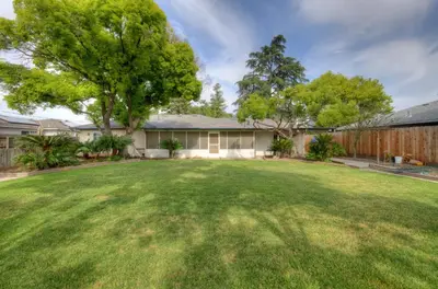 a yard with a house and a fence at The Cedar Tree in Fresno