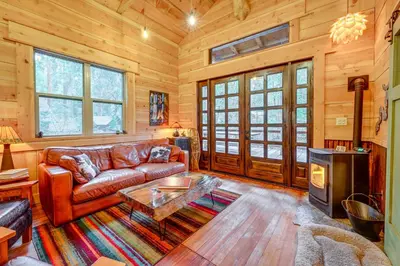 a living room with a leather couch and a table at Creekside Cabin about 20 Mi to Kings Canyon Park! in Badger