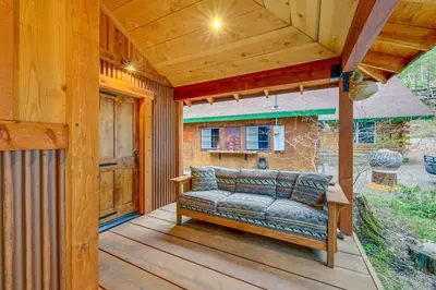 a porch with a couch on a wooden deck at Creekside Cabin about 20 Mi to Kings Canyon Park! in Badger