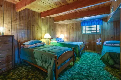 two beds in a room with wooden walls at Hike, Bike and Golf Peaceful Cabin in Twain Harte! in Twain Harte