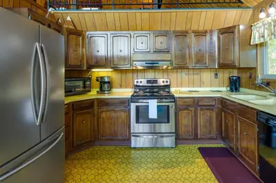 a kitchen with wooden cabinets and a stainless steel refrigerator at Hike, Bike and Golf Peaceful Cabin in Twain Harte! in Twain Harte