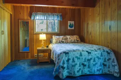 a bedroom with a bed with a blue comforter at Hike, Bike and Golf Peaceful Cabin in Twain Harte! in Twain Harte