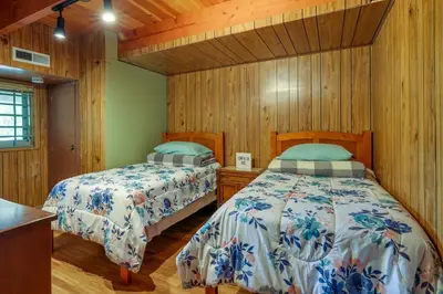 two beds in a room with wooden walls and wooden floors at Hike, Bike and Golf Peaceful Cabin in Twain Harte! in Twain Harte