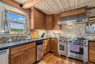 a kitchen with wooden cabinets and stainless steel appliances at Marina Beach Lodge - Lakefront Home on Beach! home in Groveland