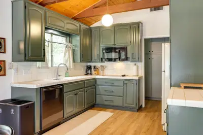 a kitchen with green cabinets and a sink at Deck and Fire Pit Stunning Twain Harte Cabin! in Twain Harte