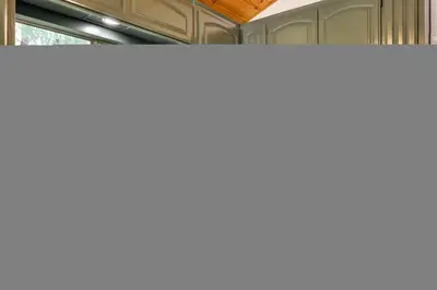 a kitchen with green cabinets and a sink and a window at Deck and Fire Pit Stunning Twain Harte Cabin! in Twain Harte