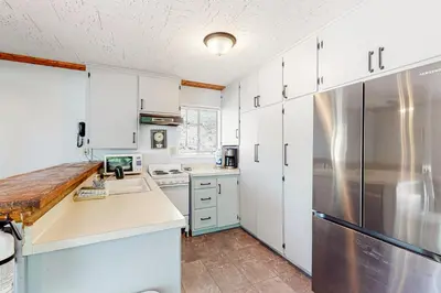 a kitchen with white cabinets and a stainless steel refrigerator at Casa de la Montaña in Bass Lake