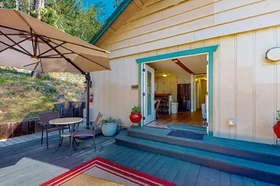 a patio with a table and an umbrella on a house at Casa de la Montaña in Bass Lake