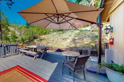 a patio with a table and chairs and an umbrella at Casa de la Montaña in Bass Lake