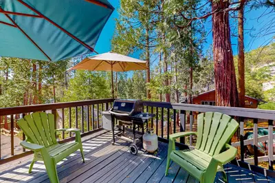 a deck with two chairs and a table with a laptop at Casa de la Montaña in Bass Lake