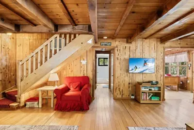 a living room with a red chair and a staircase at 3BR Mountain Cabin-Near Beach & Slopes in Homewood