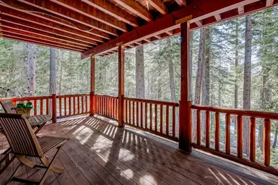 a wooden porch with two chairs and trees at Tahoe Discovery in South Lake Tahoe