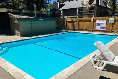 a blue swimming pool with a chair and a lawn chair at Mountain Shadows H6 in Mammoth Lakes