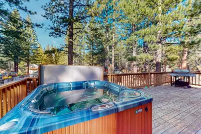 a hot tub on a deck with trees in the background at Heavenly Lake Hideaway in South Lake Tahoe