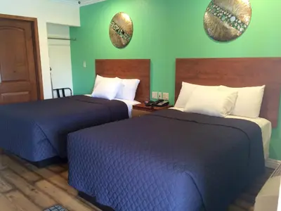 a hotel room with two beds and two mirrors on the wall at FairBridge Inn & Suites Gateway to Yosemite in Merced