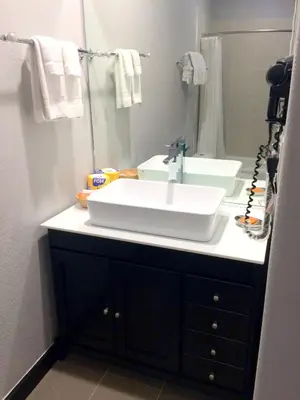 a bathroom with a white sink and a mirror at FairBridge Inn & Suites Gateway to Yosemite in Merced