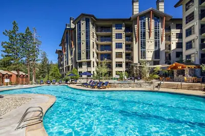 a large swimming pool with chairs in front of a building at Village Monache #309 condo in Mammoth Lakes
