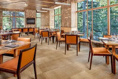 a restaurant with wooden tables and chairs andwindows at Village Monache #309 condo in Mammoth Lakes