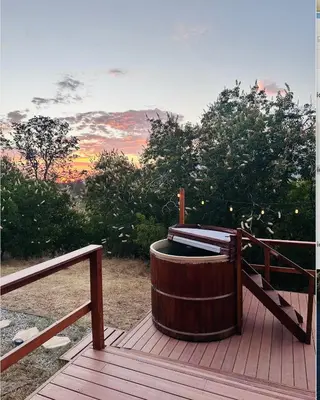 a hot tub sitting on a wooden deck with a sunset at Modern House on 5 acr in Sequoia National Forest in Panorama Heights