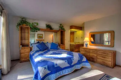 a bedroom with a blue and white bed and a mirror at Ski Lake Lodge home in Incline Village