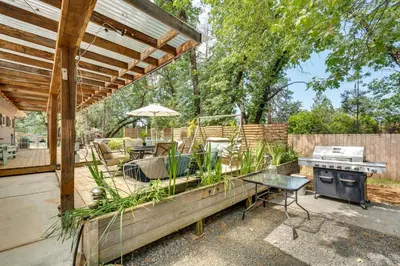 a patio with a grill and a table and an umbrella at Modern Meadow Vista Vacation Home with Spacious Deck in Meadow Vista