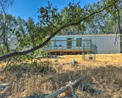 a house with a deck in the middle of a field at Blue Mountainview in Mariposa
