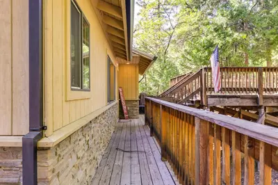 a porch of a house with a flag on it at Cozy Mi-Wuk Village Cabin with Deck! in Mi-Wuk Village