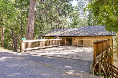 a house with a wooden bridge in the woods at Cozy Mi-Wuk Village Cabin with Deck! in Mi-Wuk Village