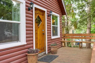 a front door of a red house with two flower pots at Fire Pit, Deck and Grill Cozy Twain Harte Cabin! in Twain Harte