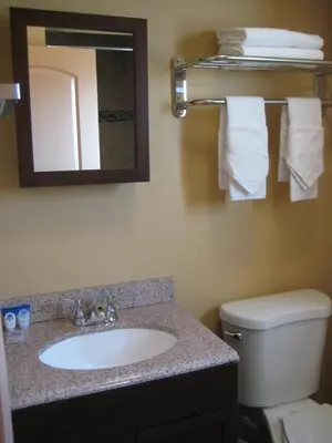 a bathroom with a sink and a toilet and a mirror at Americas Best Value Inn - Porterville in Porterville