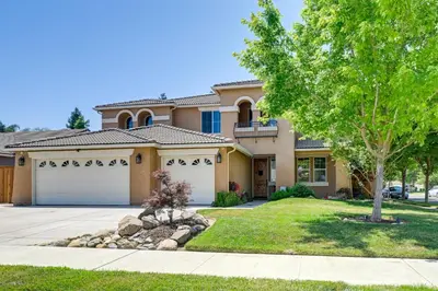 a house with two garage doors and a tree at California Vacation Rental with Private Pool and Patio in Visalia