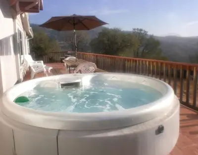 a hot tub on a deck with an umbrella at Mariposa Ridge Retreat in Mariposa
