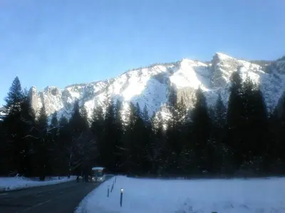 a bus driving down a road with a snow covered mountain at Mariposa Ridge Retreat in Mariposa