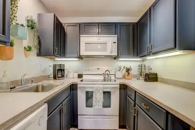 a kitchen with black cabinets and white appliances at Private condo steps from ski lift minutes to lake in Stateline