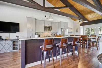 a kitchen with white cabinets and a bar with bar stools at 10 Mi to Palisades Tahoe! Condo with Game Room in Tahoe City