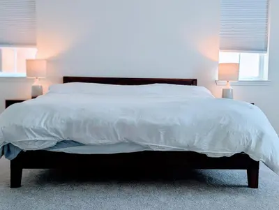 a bed with a white comforter and two lamps at Modern, Spacious & Relaxing Home in Sparks, NV in Sparks