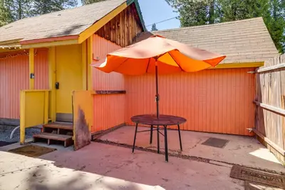 a table with an umbrella in front of a building at Dodge Ridge Pinecrest Mountain Cabin Near Hiking! in Cold Springs