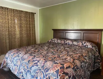 a bedroom with a large bed with a comforter at Oak Motel Modesto CA in Modesto