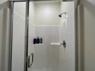 a shower with a glass door with two bottles on it at Brand-New, Beautiful & Stylish Home in Sacramento! in Sacramento
