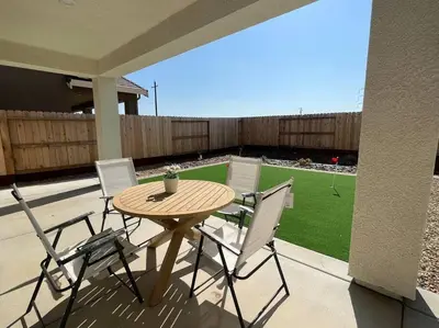 a wooden table and chairs on a patio with a yard at Brand-New, Beautiful & Stylish Home in Sacramento! in Sacramento