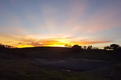 a sunset on top of a hill with the sun setting at A Great Riverfront Retreat a Shangri-La Paradize in Valley Springs