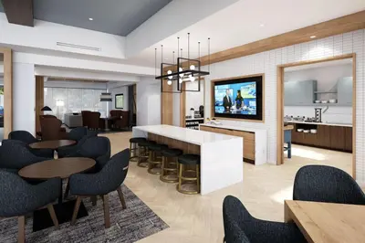 a living room with tables and chairs and a kitchen at Staybridge Suites Manteca by IHG in Manteca
