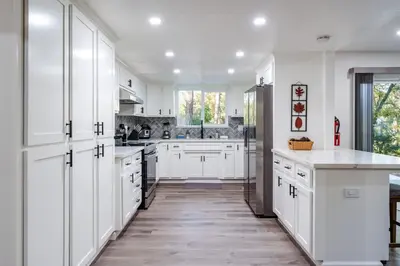 a white kitchen with white cabinets and a counter at A Modern Hideaway - with hot tub, game room, and more in Oakhurst